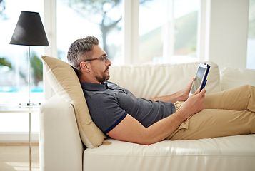 Image showing Man, relax and tablet on living room couch, reading and social media for video, game or movies in home. Mature guy, digital touchscreen and lounge sofa for internet blog, news or web app in house