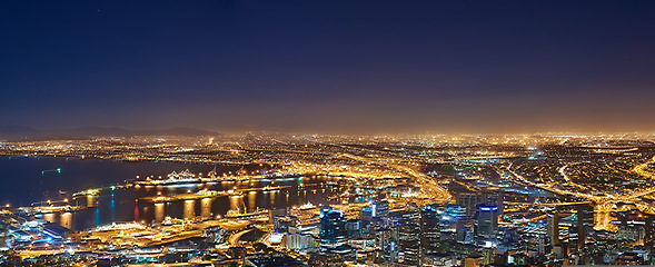 Image showing Lights, buildings and drone of the city at night with urban development, sea water and streets. Dark, travel and aerial view of outdoor residential architecture of downtown with a harbour in evening.