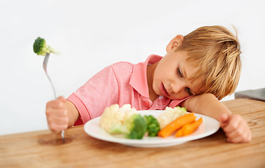 Image showing Sad, diet and a child with vegetables for dinner, unhappy meal and problem with food. Frustrated, hungry and dislike of boy kid eating broccoli, carrots and disappointed with healthy lunch at home