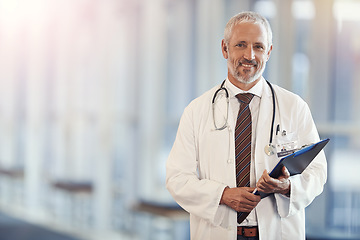 Image showing Portrait, healthcare and documents with a senior doctor standing in a hospital corridor for insurance or treatment. Medical, trust or clipboard with a man medicine professional in a clinic for health