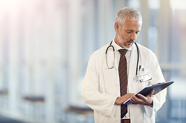 Image showing Documents, healthcare and insurance with a senior doctor standing in a hospital corridor for treatment or diagnosis. Medical, trust and clipboard with a man medicine professional in a health clinic