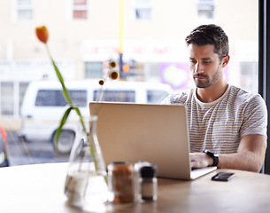Image showing Coffee shop, working and serious man with laptop and code work in a cafe. Tech, email and male freelancer customer at a restaurant table with online pc and computer writing with focus on web coding