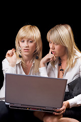 Image showing Two young businesswomen sitting with laptop. Isolated