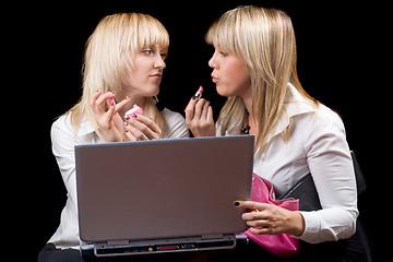 Image showing Two blondes do makeup in front of the laptop screen. Isolated