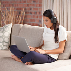 Image showing Shocked, home and woman with headphones, laptop and internet connection on sofa listening to music. Female person relax on couch to listen to wow, surprise or fake news announcement online with tech