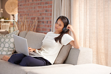 Image showing Headphones, laptop and home with woman listening to music, streaming movies and tech. Female person relax on sofa at computer for online radio, elearning blog and remote work with internet connection