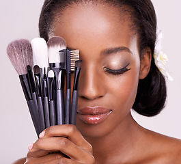 Image showing Cosmetic tools, makeup and black woman with brushes, face on studio background with application tool. Skincare, beauty and cosmetics, facial skin care model with luxury contour tools and closed eyes.