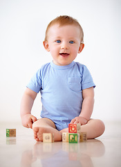 Image showing Happy, baby with toy blocks and playing against a white background with smile. Child development or learning, happiness or health wellness and boy toddler play against a studio backdrop on floor