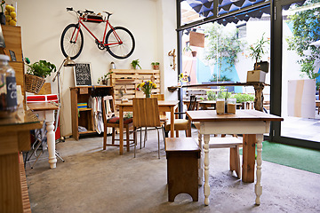 Image showing Coffee shop, empty interior and space with table, chairs and furniture or small business, bistro and cafe with unique design and style. Background, creative startup and food store with bike on wall