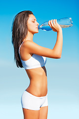 Image showing Fitness, woman and drinking water for hydration after workout, exercise or training against a blue sky background. Thirsty, active and fit female with drink bottle for refreshment or recovery