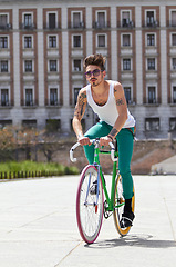 Image showing Bicycle, fitness and young man in city for travel and carbon footprint, gen z streetwear and casual fashion. Cool person or student in sunglasses and bike transport for exercise at campus building