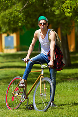 Image showing Bicycle, park and portrait of young man for travel, journey and carbon footprint, streetwear and cool fashion at university. Person or college student in sunglasses, bike transport and outdoor campus