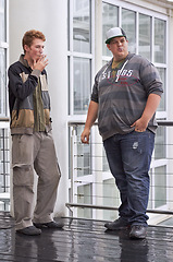 Image showing Teen men, friends and smoking outside education and school building outdoor. Rebel, guys and teenager students with tobacco and cigarette smoke in the rain with a male young friend of university