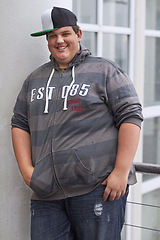 Image showing Plus size, young man and portrait outdoor with hipster and urban style with a smile. Happy, gen z fashion and cool clothing of a heavy male person with youth and confidence with hands in pockets