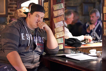 Image showing Man portrait, pub and plus size person waiting for a alcohol and beer drink looking serious. Male person, restaurant and alcoholic sitting at a counter at a club with gen z, cool and urban fashion