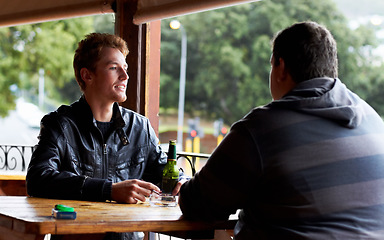 Image showing Men, friends and drinking beer at a pub and restaurant with conversation and discussion. Alcohol, guys and young people together at diner with alcohol and drink with bottle and cigarette at table