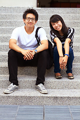 Image showing Portrait, education and an asian couple on steps, sitting outdoor at university together for learning. Love, study or college with a man and woman student on stairs to relax while bonding at break