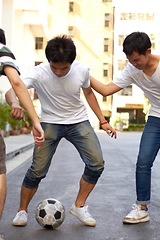 Image showing Friends in road playing with soccer ball together for sports, fun and happy energy, urban games in Korea. Football game for teen friendship, group in Asian city street with weekend time in community.