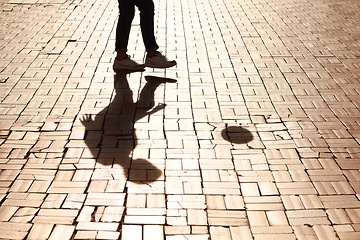 Image showing Sports, soccer and man shadow with a ball training for a skill, trick or stunt on a pavement. Silhouette, football and legs of a male person practicing for a game, match or tournament in the city.