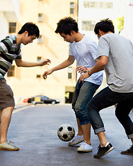 Image showing Friends in street playing football together for sports, fun and happy energy with urban games in Korea. Games for kids, friendship and teen group in road with soccer ball, weekend time in Asian city.