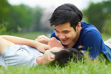 Image showing Asian men, gay couple and lying in park, grass or garden with love, care and bonding with kiss in summer. Happy Japanese guy, romantic and relax together on lawn for lgbtq, smile, outdoor in nature