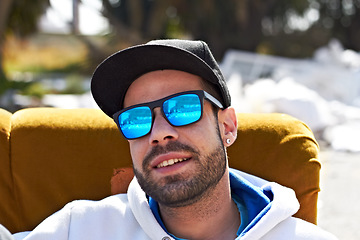 Image showing Man, portrait and sunglasses with smile on street for urban fashion or cool summer style in the city. Happy male person or face of stylish model with cap smiling and relaxing on chair in the outdoors