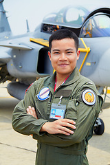 Image showing Portrait of man, pilot in military with jet and confident smile at airforce base with arms crossed in Korea. Freedom, transport and proud Asian soldier with airplane, confident and service in army.