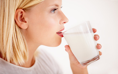 Image showing Profile, milk or nutrition with a woman drinking from a glass in studio isolated on a white background. Health, detox and calcium with a young female enjoying a drink for natural vitamins or minerals