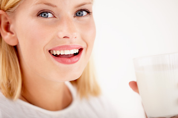 Image showing Portrait, milk and happy with a woman drinking from a glass in studio isolated on a white background. Smile, nutrition or calcium with a healthy young female enjoying a drink for vitamins or minerals