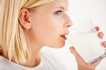 Image showing Face, milk and thinking with a woman drinking from a glass in studio isolated on a white background. Idea, nutrition and calcium with a healthy young female enjoying a drink for natural vitamins