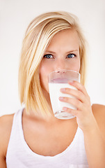 Image showing Portrait, milk and a woman drinking from a glass in studio isolated on a white background. Health, nutrition and calcium with a young female enjoying a drink for natural vitamins in the morning