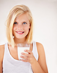 Image showing Portrait, milk and health with a woman drinking from a glass in studio isolated on a white background. Healthy, nutrition and calcium with a young female enjoying a drink for vitamins or minerals