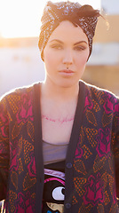 Image showing Portrait, fashion and serious woman in city with scarf on head, urban tattoo and stylish. Face, street and trendy female person from Norway in cool clothes, attitude and body art outdoor at sunset.