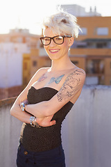 Image showing Glasses, portrait and woman in city with arms crossed for stylish tattoo, body art and fashion. Hipster, street and confident female person standing outdoor in Australia, happy and punk attitude.