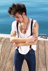 Image showing Punk dress code, man with tattoos and on pier outdoors at the beach. Health wellness, travel or journey and male fashion model with tattoo ink on his body outside of the sea for nature fresh air