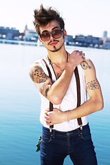 Image showing Sunglasses, portrait and serious man by sea with stylish tattoo, body art and fashion. Punk, ocean and trendy male person standing outdoor in Spain with cool clothes, attitude and aesthetic mockup.