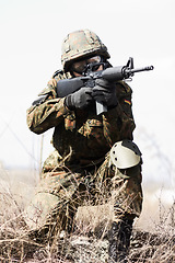 Image showing Soldier man, machine gun and outdoor with aim, field and nature for war, fight and army in countryside. Military service, battlefield and agent with weapon, gear and helmet for conflict in Ukraine