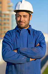 Image showing Man, architect and portrait smile in construction with arms crossed and hard hat in the city. Male person, engineer or contractor smiling in confidence for industrial architecture or building in town