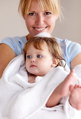 Image showing Portrait, mother and baby with happiness in a towel for bath with bond and love in a closeup at house. Child, care and mom with towel for hug for comfort and affection with smile in family home.