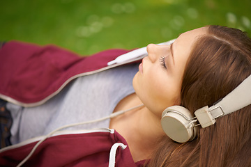 Image showing Woman, student and headphones for music on grass to relax, summer and audio streaming subscription. Girl, campus lawn and park with meditation sound, sleep and peace for listening, radio and podcast