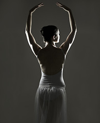 Image showing Art, silhouette and back of a ballet dancer in a studio with elegant posture, pose or position. Creative, monochrome and female ballerina doing a classical dance or performance by a black background.