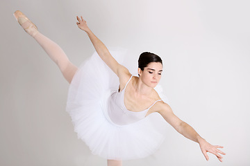 Image showing Balance, dance and ballet with a woman in studio on a white background for rehearsal or recital for theatre performance. Art, creative and elegance with a young female ballerina or dancer in uniform