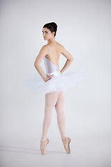 Image showing Portrait, dance and ballet with a woman in studio on a white background for theatre performance rehearsal or recital. Art, creative and back with a young ballerina or dancer standing hands on hips