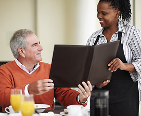 Image showing Waitress, menu and senior man in a restaurant for breakfast or lunch at a hotel with service and choice of food. Friendly, order and elderly person happy on vacation or holiday for hospitality