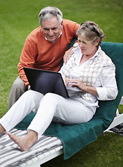 Image showing Retirement, laptop and an old couple in the garden of a hotel for travel or vacation at a luxury resort. Love, technology or social media with a senior man and woman tourist on a deckchair at a lodge