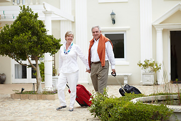 Image showing Travel, hotel and happy senior couple walking with suitcase in a holiday or vacation location in retirement together. Bag, smile and elderly people on a journey or man and woman walk in happiness