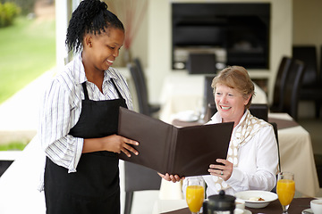 Image showing Waitress, service and senior woman in a restaurant for breakfast or lunch at a hotel with a menu and choice of food. Friendly, order and elderly person happy on vacation or holiday for hospitality