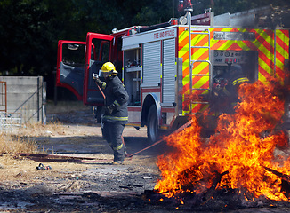 Image showing Fire, training and truck with firefighter and emergency in nature for smoke, safety and explosion. Danger, fearless and teamwork with group of men in outdoor for rescue, saving operation and action