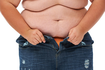 Image showing Weight gain, plus size and jeans of a person with overweight and stomach issue in studio. White background, model and casual fashion too tight from stomach and waist wellness problem of pants