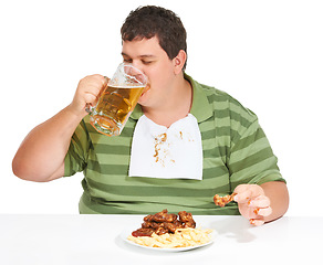 Image showing Obesity, man and fast food with alcohol, unhealthy and guy isolated against a white studio background. Obese, male person and model with beer, chicken wings and eating with a bib, fries and hungry